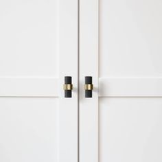 two black knobs on white doors with gold accents in the handles and bottom part