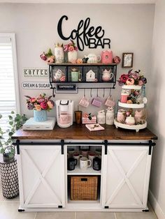 a coffee bar is decorated with pink flowers and other decor items, such as cakes