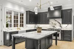 a large kitchen with marble counter tops and black cabinets