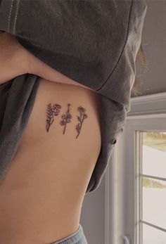 the back of a woman's stomach with three small flowers on it