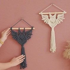 a hand is holding a piece of yarn next to a crocheted wall hanging