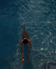 a woman floating in the water on top of a surfboard next to a swimming pool