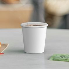 a cup of coffee sitting on top of a table next to a donut