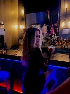 a woman sitting at a bar with a drink in her hand