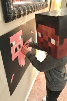 a young boy is making a paper minecraft head