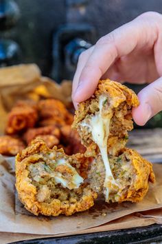 a person is holding something in their hand with food inside it and on the table