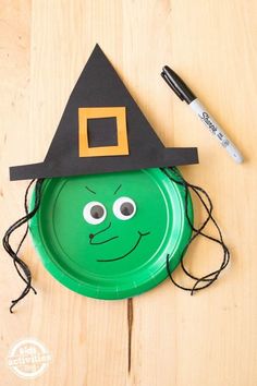 a green frisbee with a black witches hat on it and a marker next to it