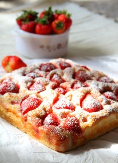 a pastry with powdered sugar and strawberries in the background on a white tablecloth