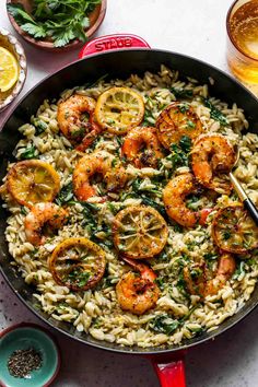 a skillet filled with pasta and shrimp, garnished with parsley on the side