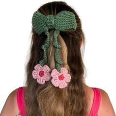 a woman with long hair wearing a green crochet bow and two pink flowers