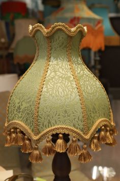 a green lamp with tassels on it sitting on top of a wooden table