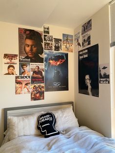 a bedroom with posters on the wall and a bed in front of it that has a headboard