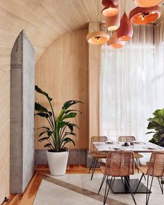 an indoor dining area with wooden walls and flooring, potted plants on the table