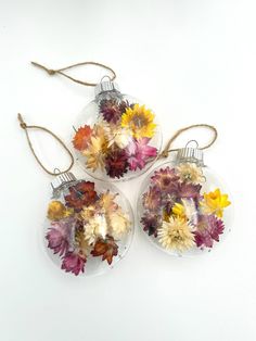 three glass ornaments with dried flowers in them