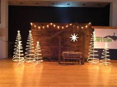 christmas trees are lit up on the floor in front of a stage set with lights