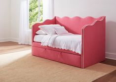 a pink day bed with white sheets and pillows