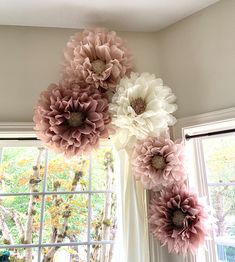 paper flowers hanging from the ceiling in front of a window