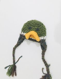 a crocheted hat with a bird's head on it and two feathers attached to the brim