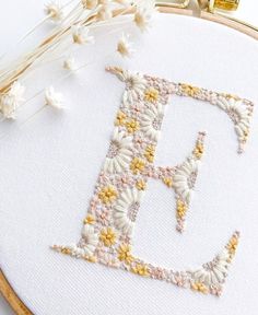 a cross stitch pattern with the letter d in it's center surrounded by flowers