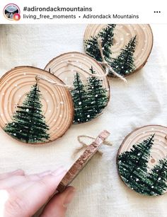 someone is decorating some wooden slices with christmas trees on them and holding a string