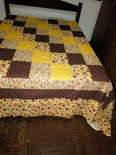 a bed with a yellow and brown quilt on it