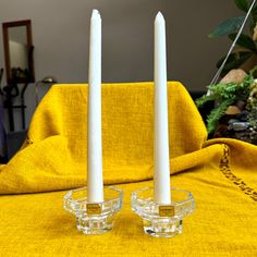 two clear candles sitting on top of a yellow blanket