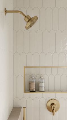 a gold faucet in a white tiled bathroom with shelves and bottles on the wall