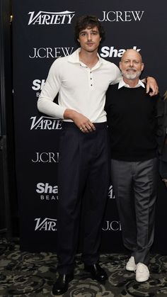 two men standing next to each other in front of a black wall with the words jcreww on it