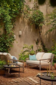 an outdoor seating area with couches, tables and potted plants on the ground