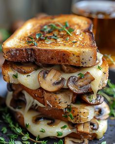 a grilled cheese and mushroom sandwich is stacked on top of each other with fresh herbs