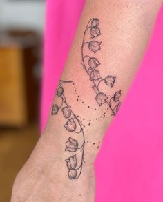 a woman's wrist tattoo with flowers and leaves on the left side of her arm