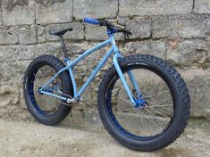 a blue bike parked against a stone wall