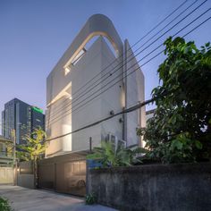 the building is white and has an arch in it's center, surrounded by greenery