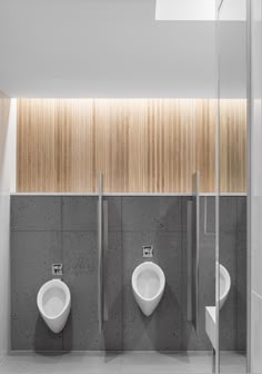 three urinals in a public restroom with wood paneling