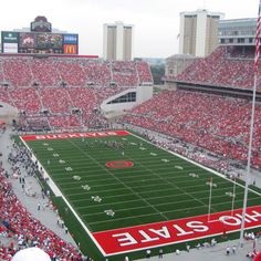 a stadium filled with lots of red and white football field covered in people sitting on the bleachers