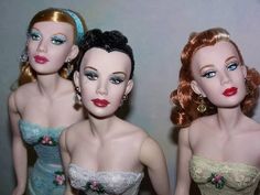 three barbie dolls are standing next to each other in dresses and tiaras with flowers on them