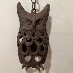 an owl sculpture hanging from a chain on a wall