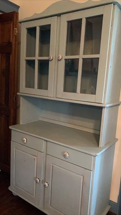 a white china cabinet with glass doors and drawers