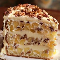 a piece of cake with white frosting and pecans on top sitting on a plate