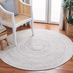 a living room with a chair, rug and potted plant on the hardwood floor