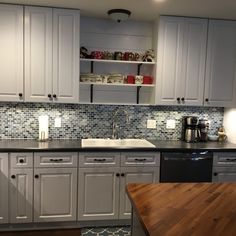 a kitchen with white cabinets and gray counter tops