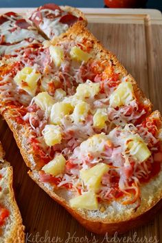 two pieces of bread with cheese and other toppings on it sitting on a cutting board