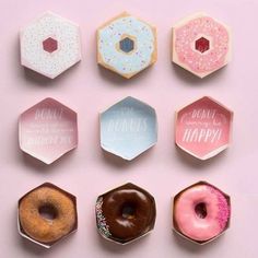 six donuts with different toppings are arranged on a pink surface