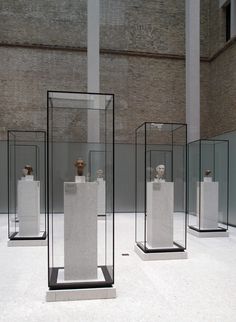 four glass cases with sculptures in them on display inside an indoor space that looks like a museum