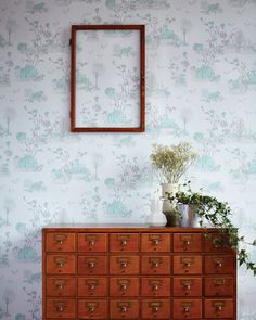 a wooden dresser sitting in front of a wall with a mirror on top of it