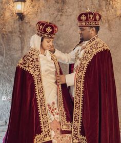 two people dressed in red and gold standing next to each other