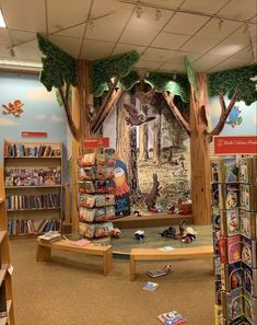 the children's book store has many books on shelves and is decorated with trees