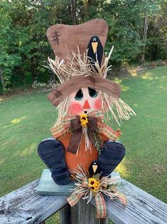 a scarecrow sitting on top of a wooden fence