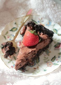 a slice of chocolate pie on a plate with a fork next to it and a strawberry in the middle