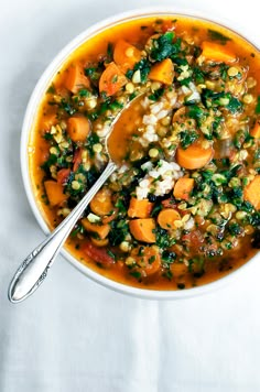 carrot, red lentil and spinach soup in a white bowl with a spoon